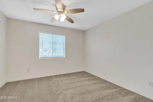 an empty room with a window and a ceiling fan