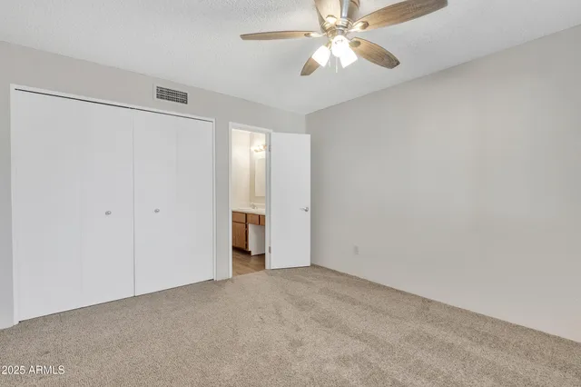 an empty room with closet and a chandelier fan