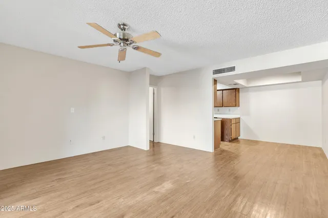 a view of an empty room with wooden floor and a ceiling fan