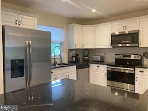 a kitchen with stainless steel appliances granite countertop a refrigerator sink and stove