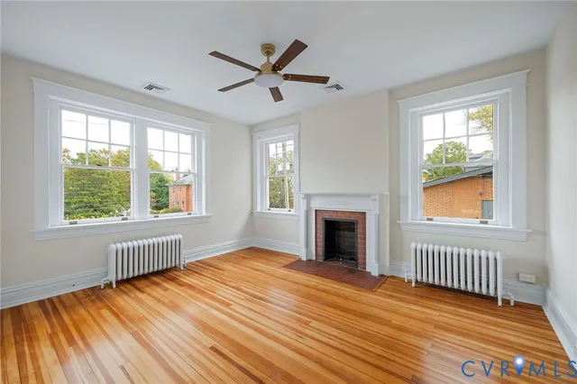 an empty room with wooden floor and a ceiling fan