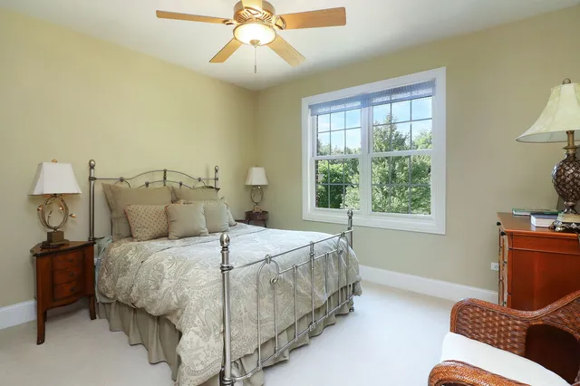 a bedroom with a bed table chair and a window
