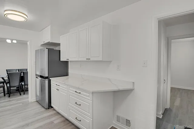 a kitchen with stainless steel appliances white cabinets and wooden floor