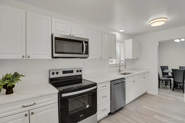 a kitchen with cabinets stainless steel appliances a sink and wooden floor