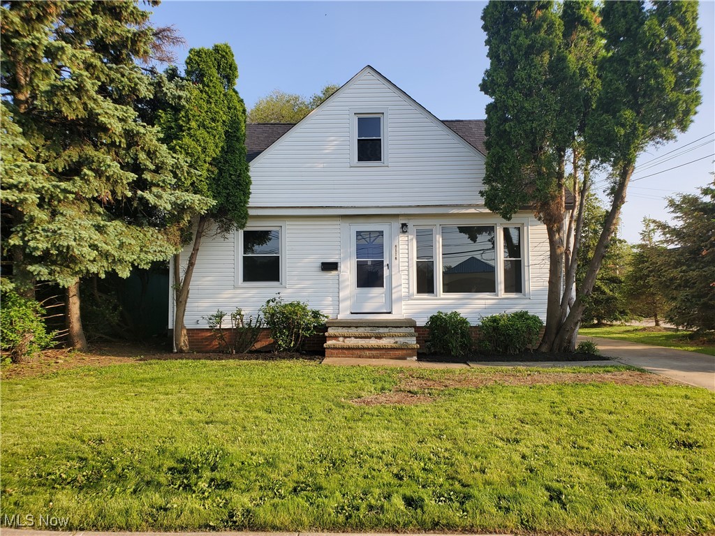 View of front of home with a front yard and a shingled roof