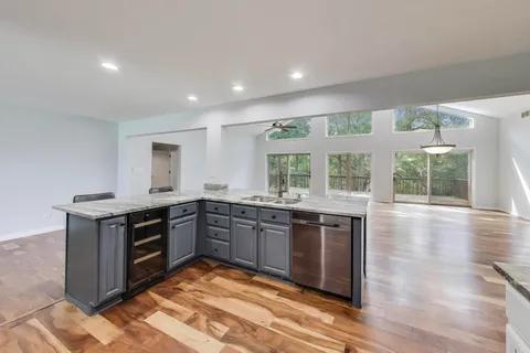 a kitchen with stainless steel appliances granite countertop a table chairs sink and cabinets