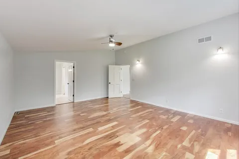 a view of empty room with wooden floor and ceiling fan