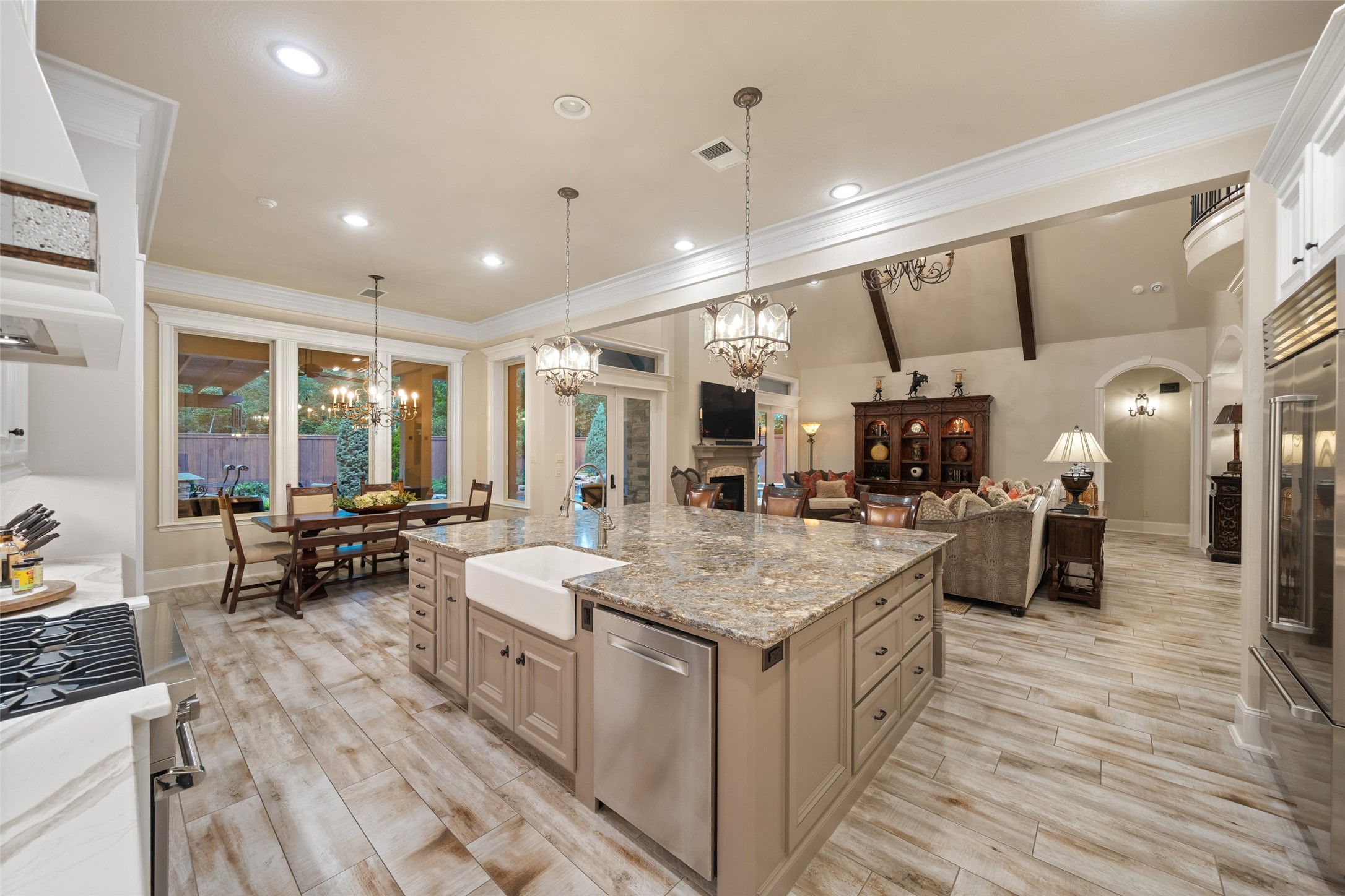 59 East Ambassador Bend Spring, TX 77382 - Photo 11 of 48 Open-concept living at its finest, this stunning space showcases a chef-inspired kitchen that seamlessly connects to the dining and living areas. The oversized island, outfitted with a farmhouse sink, Bosch dishwasher, storage, and refrigerated beverage drawers, anchors the room. The island also serves as a breakfast bar and beckons guests to sit and chat with the chef!
