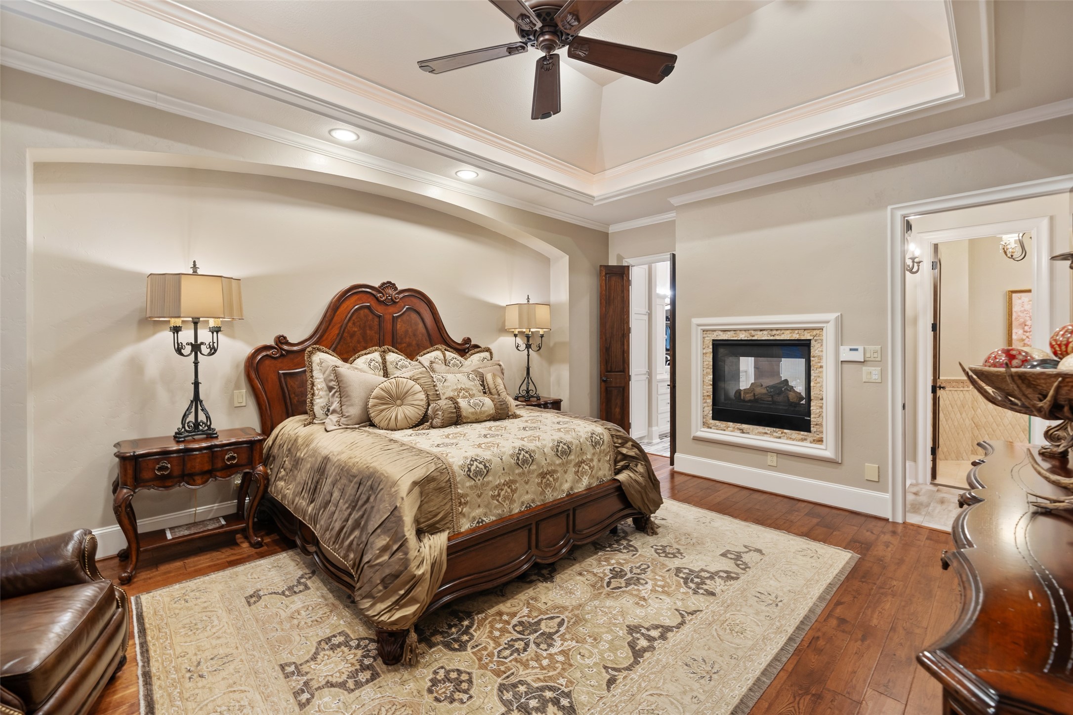 59 East Ambassador Bend Spring, TX 77382 - Photo 16 of 48 The primary bedroom features wood floors, double sided gas fireplace and deep tray ceiling with crown molding. Double doors lead to the lovely primary bathroom.