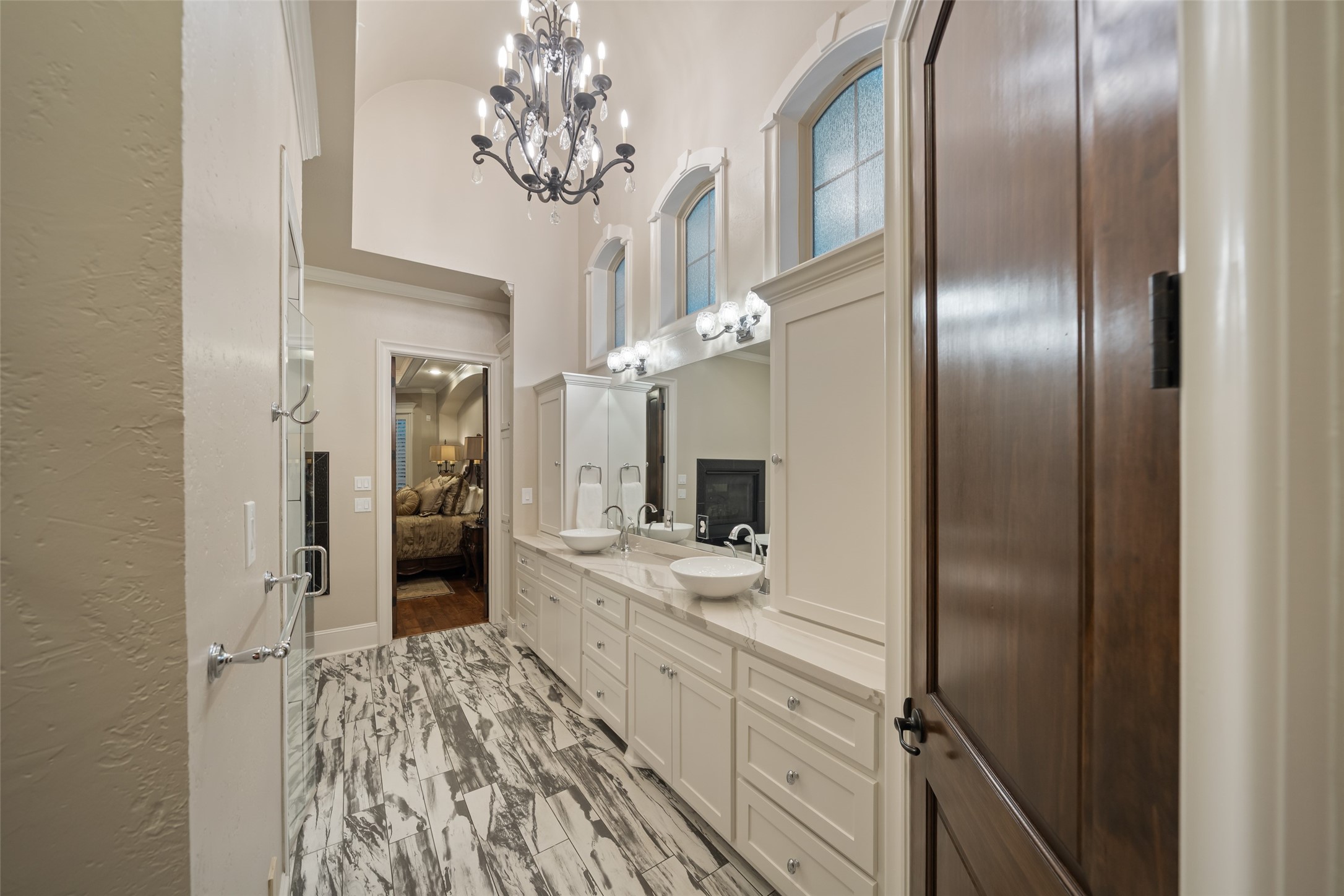 59 East Ambassador Bend Spring, TX 77382 - Photo 18 of 48 The primary bathroom impresses with its dramatic ceiling height, elegant chandelier, and transom windows that flood the space with soft, natural light.