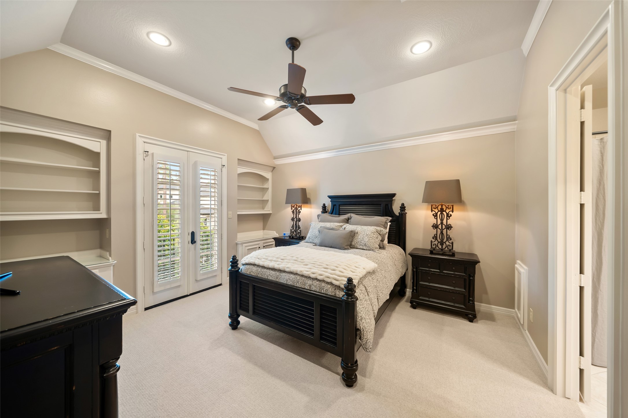 59 East Ambassador Bend Spring, TX 77382 - Photo 28 of 48 Three secondary bedroom suites are located on the second level. This secondary bedroom features French doors opening onto a balcony, allowing natural light and fresh air to flow into the space. The room features wool carpeting, cove ceilings that enhance the sense of openness along with a built-in desk that adds both functionality and a custom feel.
