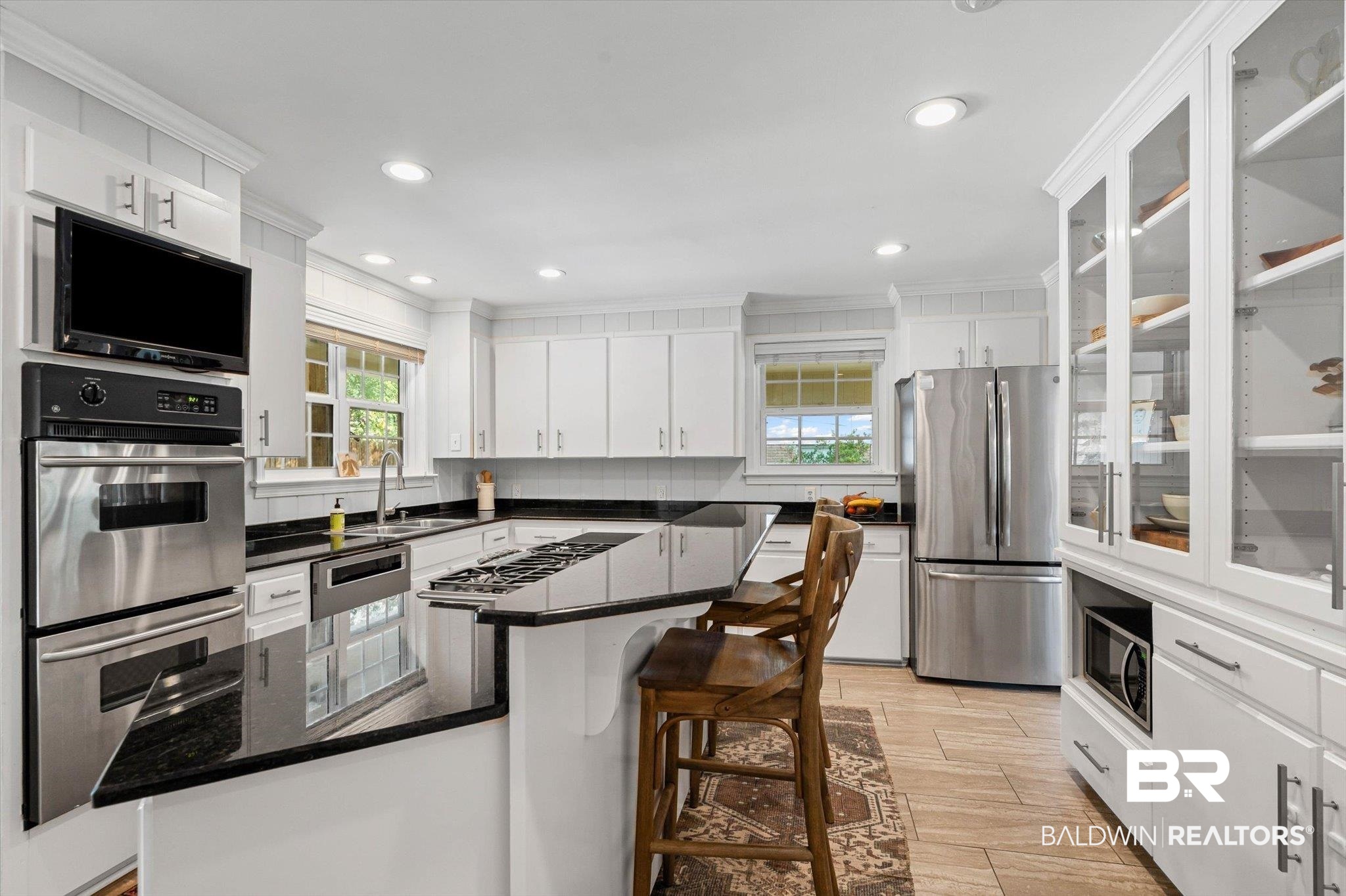 313 Brawood Drive Mobile, AL 36608 - Photo 9 of 32 Kitchen featuring a kitchen bar, stainless steel appliances, white cabinets, light wood-style floors, and dark stone countertops