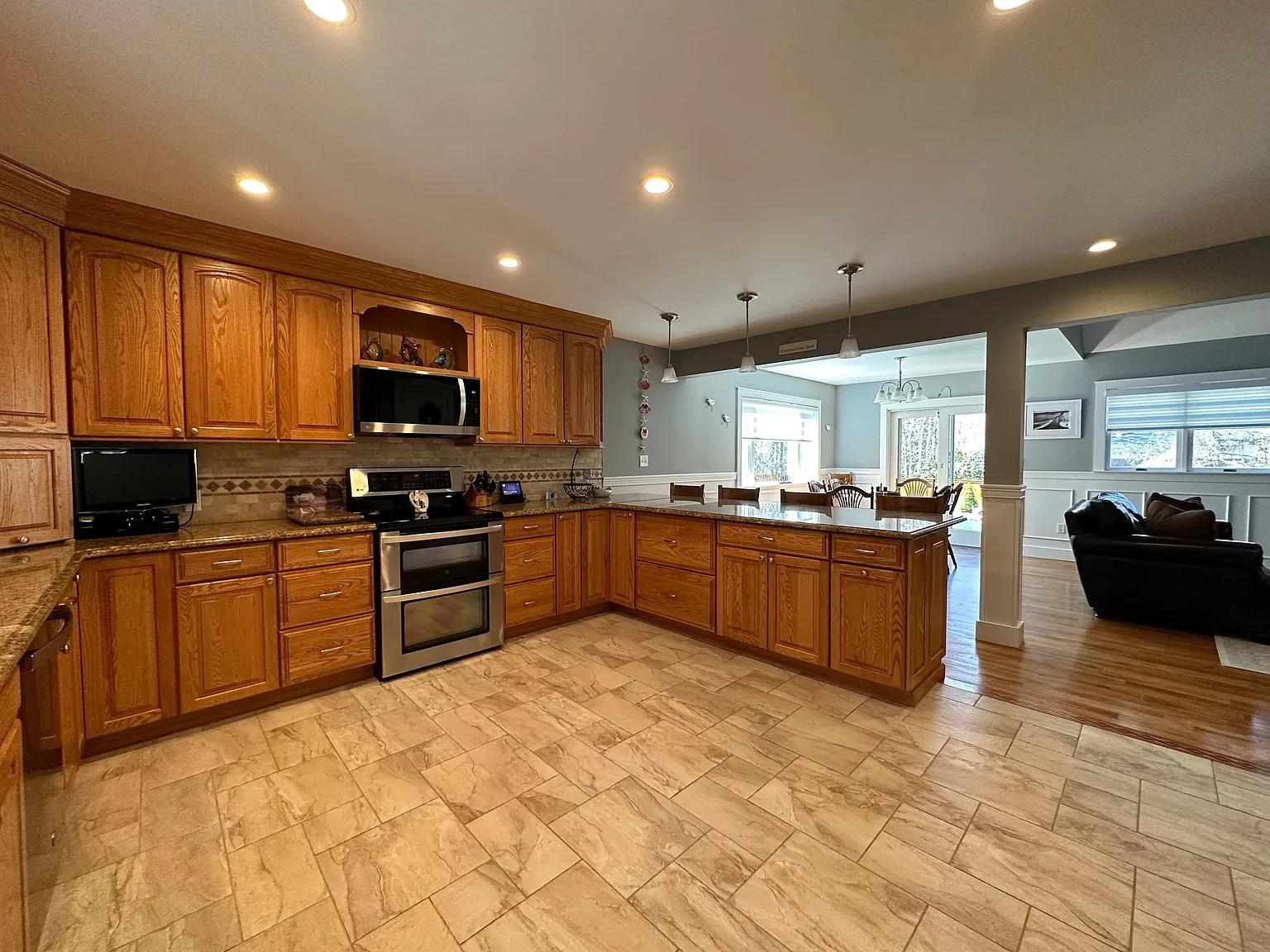 5 Spruce Street East Hampton, NY 11937 - Photo 6 of 16 Kitchen featuring decorative light fixtures, recessed lighting, a peninsula, appliances with stainless steel finishes, and brown cabinets