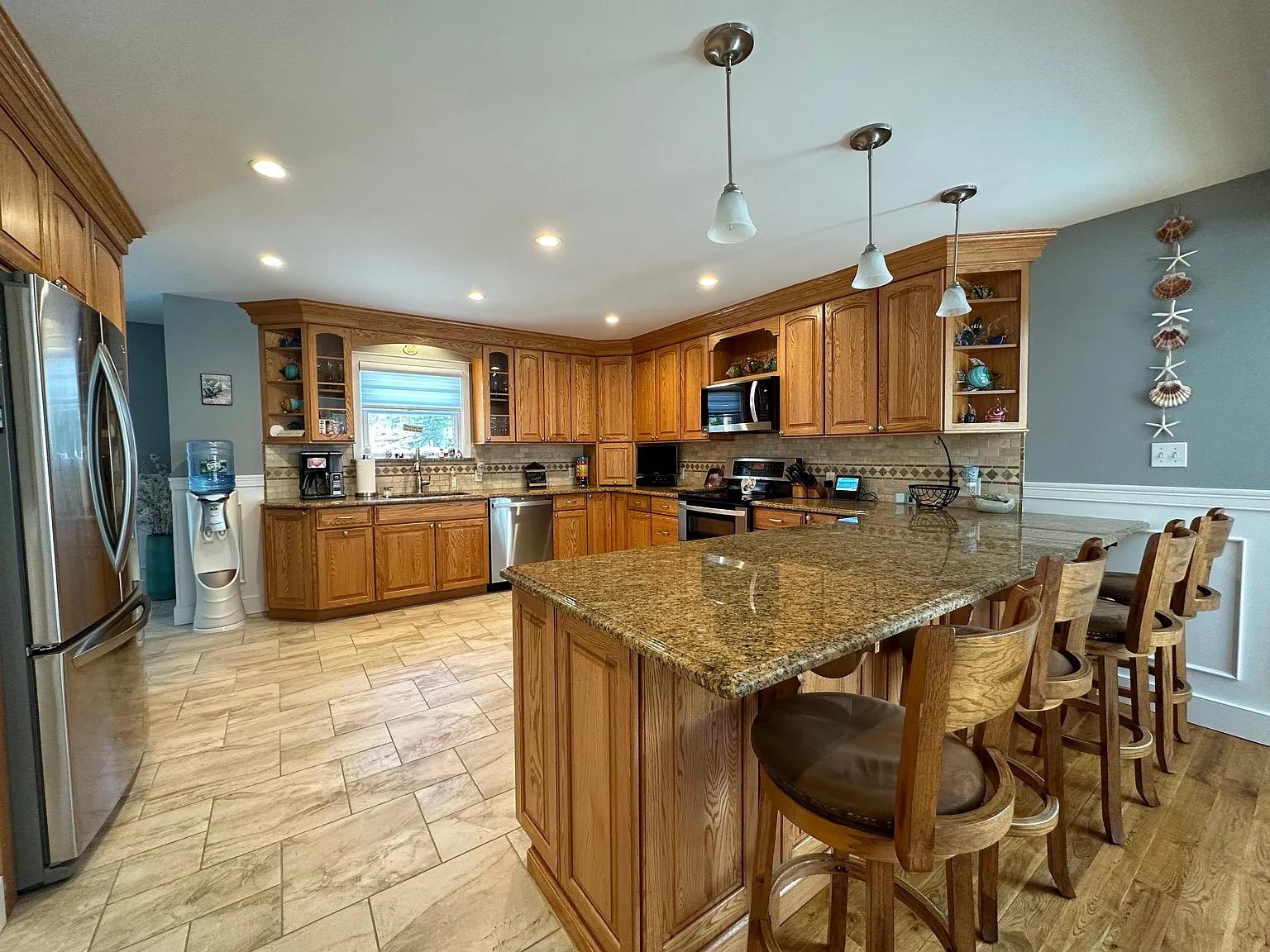 5 Spruce Street East Hampton, NY 11937 - Photo 7 of 16 Kitchen with open shelves, a sink, a peninsula, appliances with stainless steel finishes, and brown cabinets