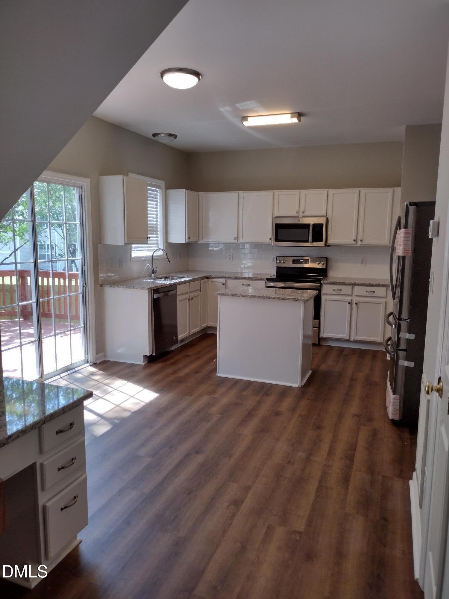 2339 School Creek Place Raleigh, NC 27606 - Photo 7 of 11 a kitchen with stainless steel appliances wooden floors and wooden cabinets