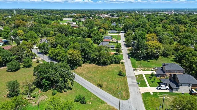 an aerial view of residential houses with outdoor space and trees