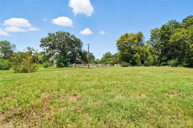 a view of a green field with trees in the background