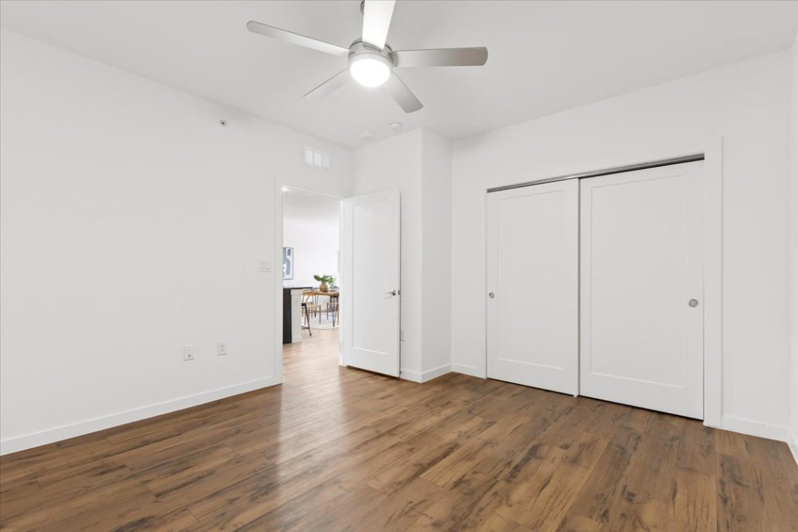 4801 Springdale Road, Unit 1107 Austin, TX 78723 - Photo 19 of 40 Unfurnished bedroom with dark wood-type flooring, ceiling fan, and a closet