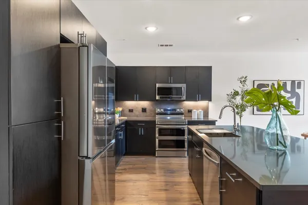 a kitchen with stainless steel appliances granite countertop a sink stove and refrigerator