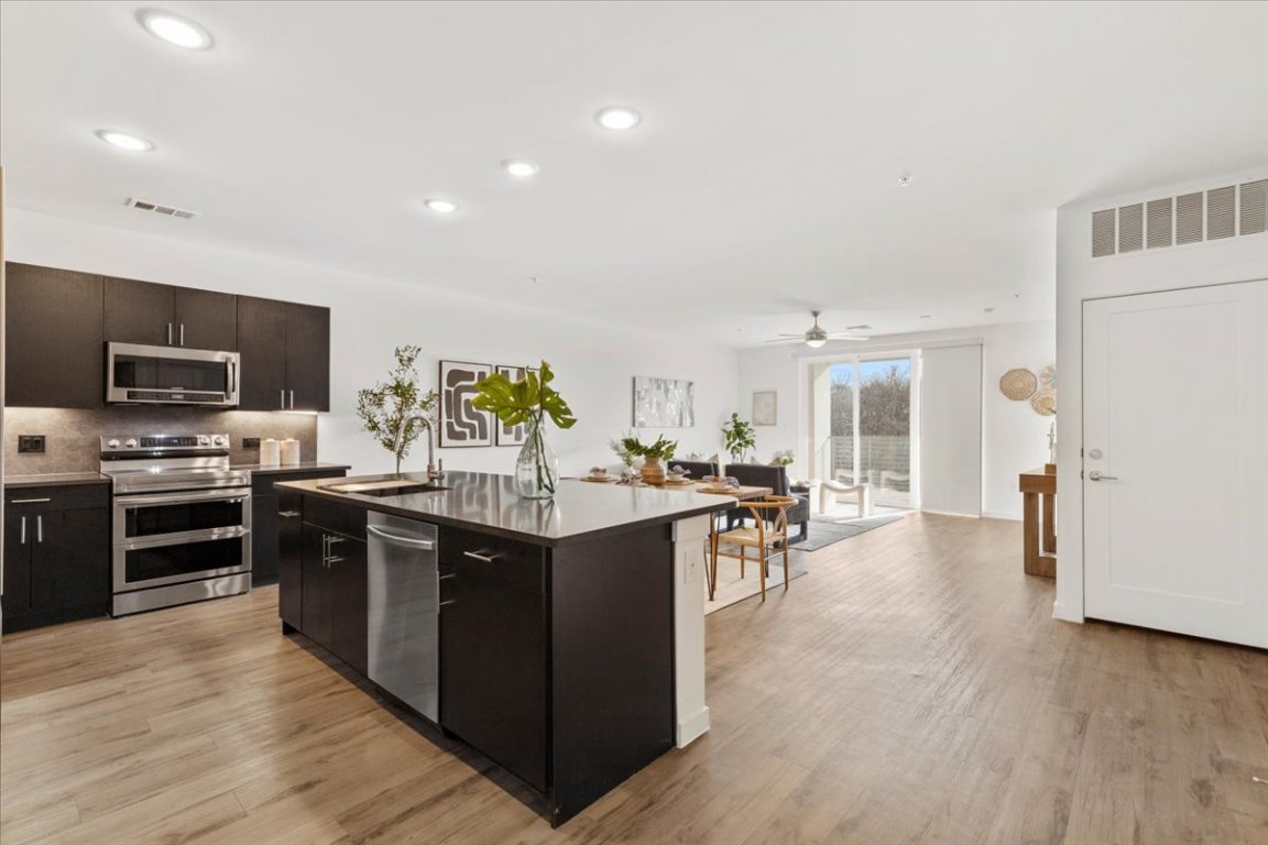 4801 Springdale Road, Unit 1107 Austin, TX 78723 - Photo 40 of 40 Kitchen featuring stainless steel appliances, a center island with sink, recessed lighting, light wood finished floors, and open floor plan