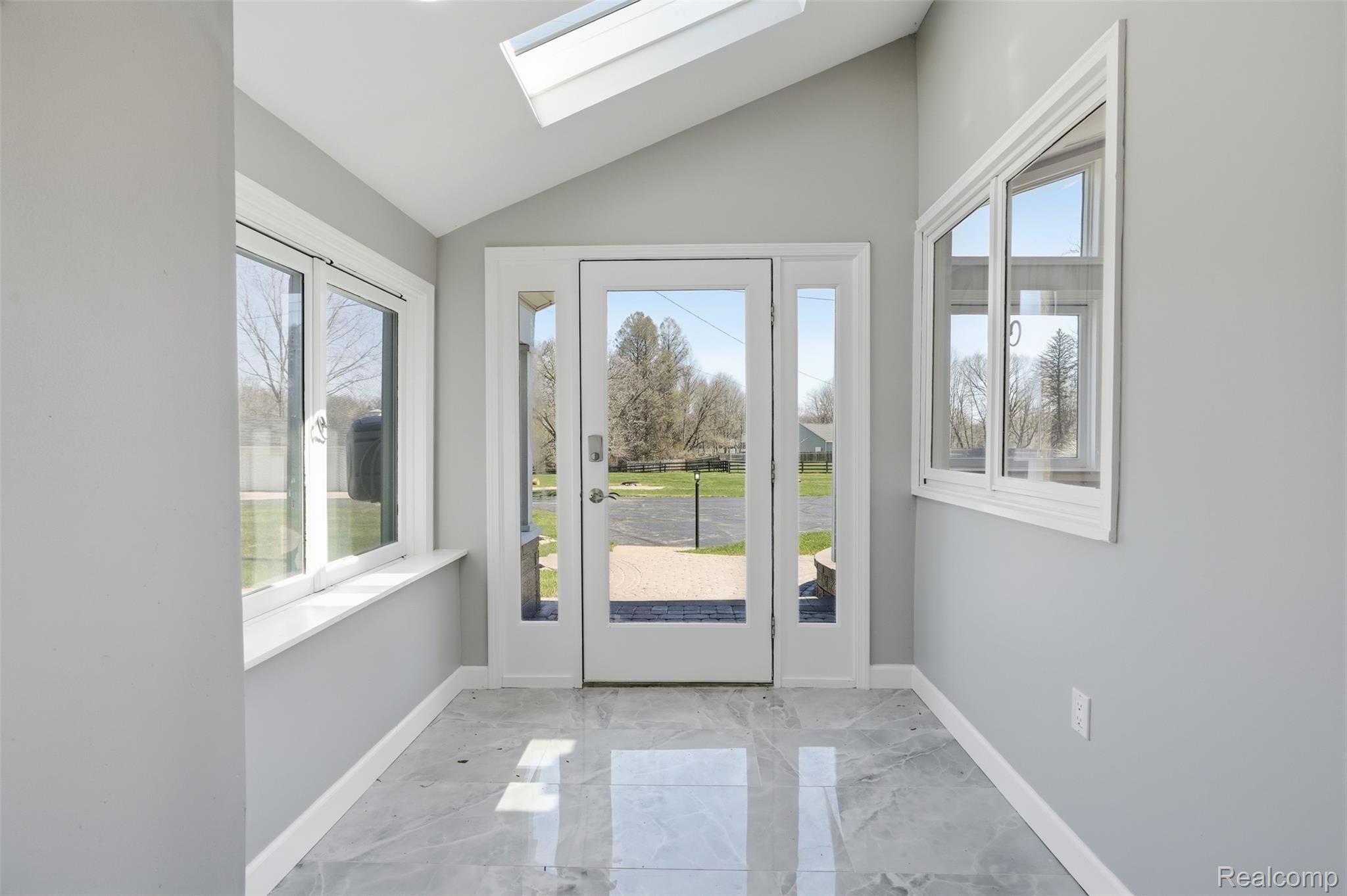 8636 Tindall Road Davisburg, MI 48350 - Photo 8 of 61 Doorway with marble tiled flooring, vaulted ceiling, and a skylight