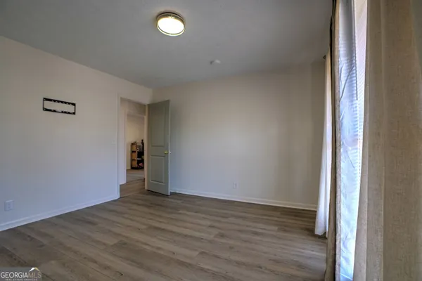 a view of an empty room with wooden floor and closet