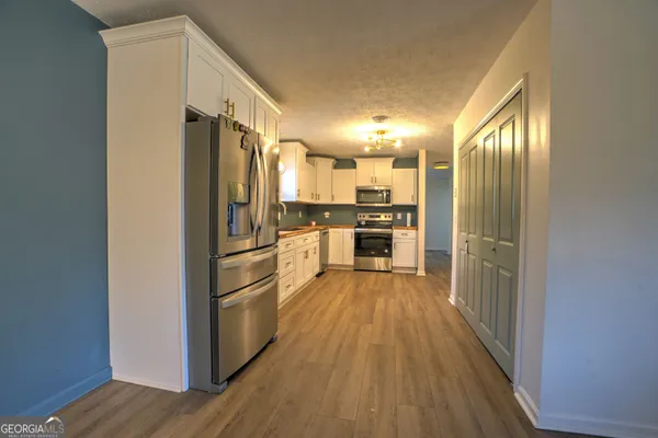 a kitchen with wooden floors stainless steel appliances and a refrigerator