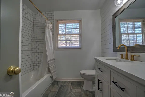 a bathroom with a granite countertop toilet a sink and a bathtub