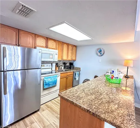 a kitchen with granite countertop a refrigerator a stove a sink and cabinets
