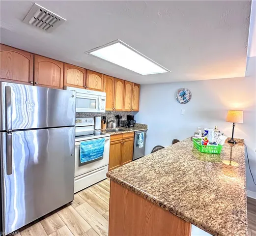 a kitchen with granite countertop a refrigerator a stove a sink and cabinets
