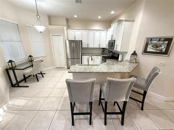 a kitchen with stainless steel appliances kitchen island granite countertop a sink a refrigerator and chairs