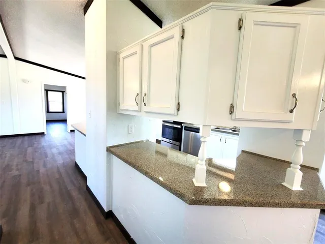 a kitchen with kitchen island granite countertop a sink a stove and cabinets