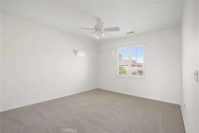 an empty room with ceiling fan and window
