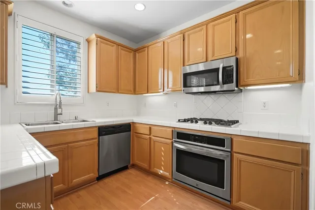 a kitchen with stainless steel appliances granite countertop a sink a stove a microwave and wooden cabinets