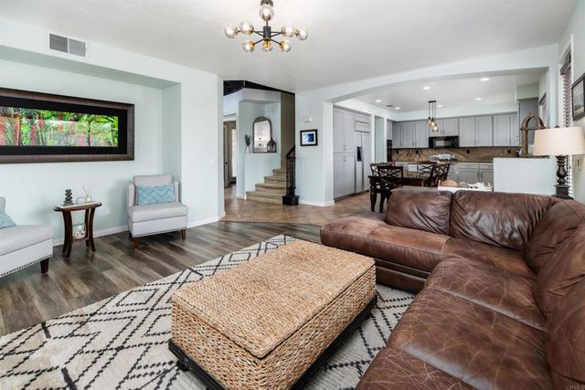 a living room with furniture a flat screen tv and kitchen view