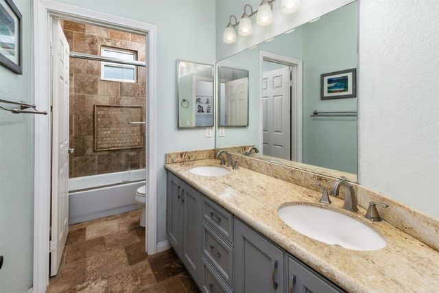 a bathroom with a granite countertop double vanity sink and a mirror