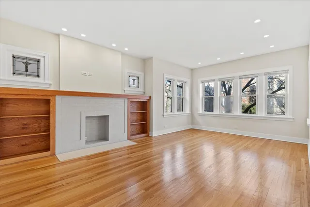 a view of an empty room with window and wooden floor