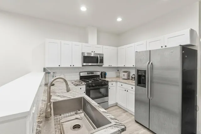 a kitchen with a sink a refrigerator and white cabinets