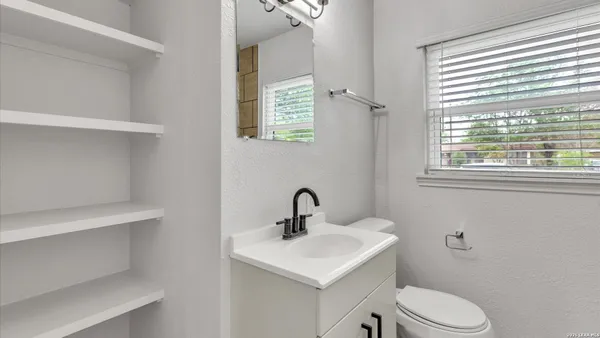 a bathroom with a sink a toilet a window and shower