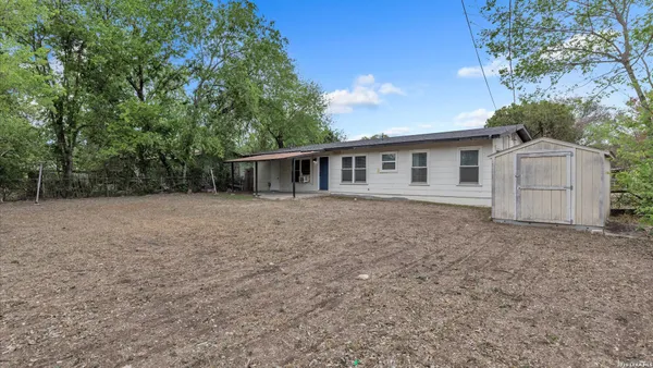 a front view of house with yard and trees in the background