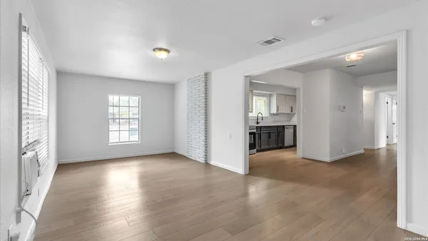 an empty room with wooden floor and windows