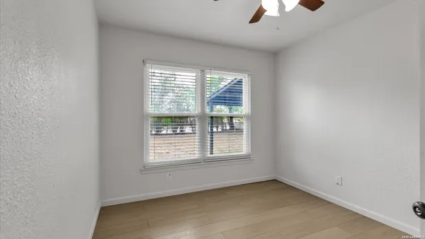 an empty room with ceiling fan and window