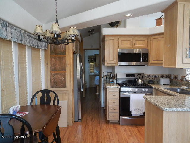 3721 Horseshoe Loop Show Low, AZ 85901 - Photo 20 of 44 a kitchen with stainless steel appliances granite countertop a stove top oven a refrigerator a sink dishwasher a dining table and chairs with wooden floor