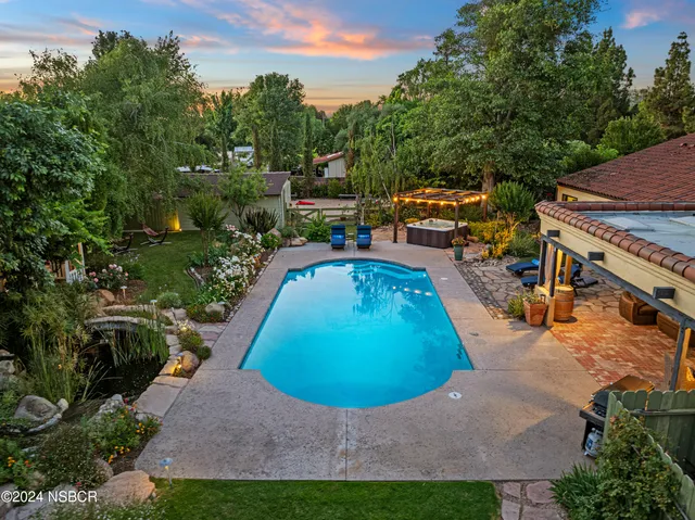 an aerial view of a house with swimming pool and large trees