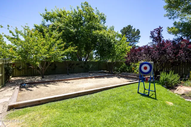 a sign board with a yard and trees in the background