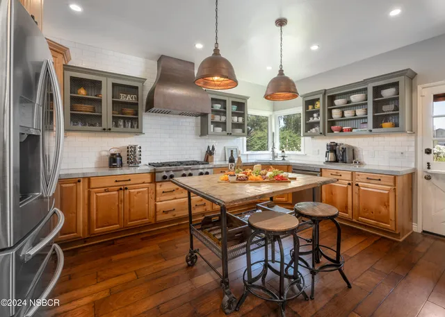 a kitchen with stainless steel appliances granite countertop a stove a sink dishwasher a dining table and chairs with wooden floor