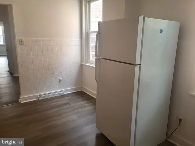 a view of a kitchen with a refrigerator and a wooden floor