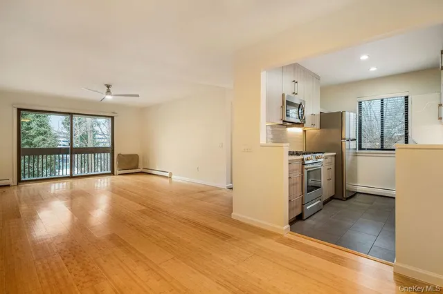 a view of a kitchen with a stove wooden cabinets and a living room