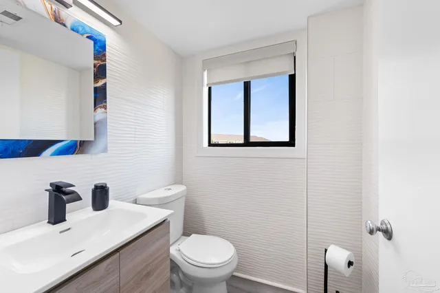 a bathroom with a toilet a sink a mirror and vanity