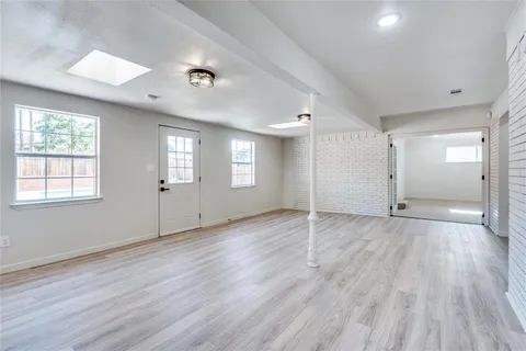 a view of an empty room with wooden floor and windows